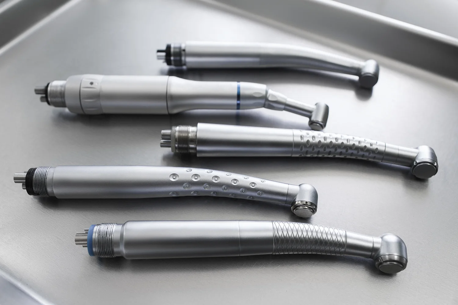 Mehrere zahnärztliche Hand- und Winkelstücke liegen zur Reparatur und Wartung im Dental Bauer Servicebereich auf einem Tray