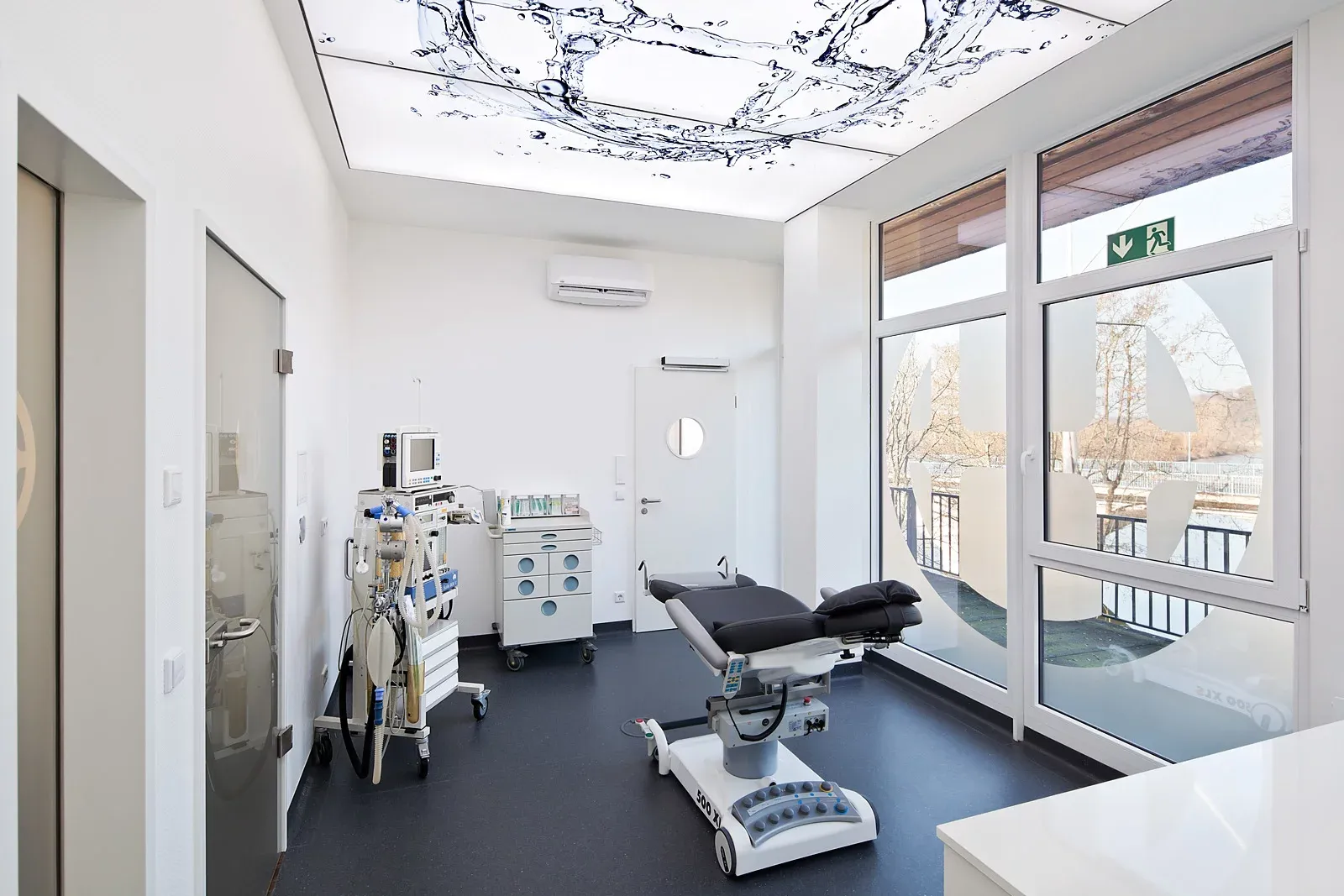 Behandlungsraum mit Behandlungsstuhl und großem Deckenbild mit Wasseranimation.