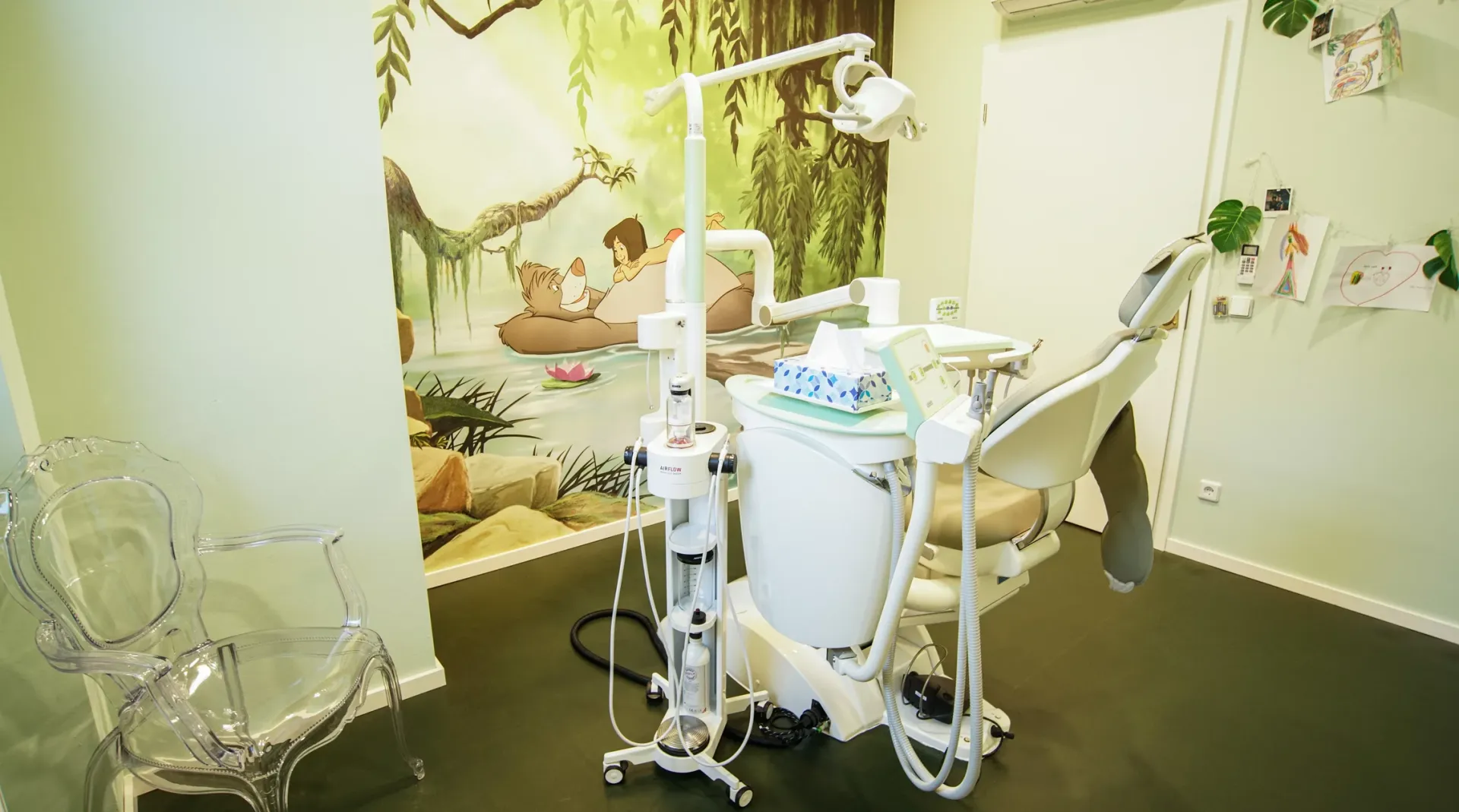 Behandlungsraum mit Dschungel-Thema und dekorativ gestalteten Wänden.
