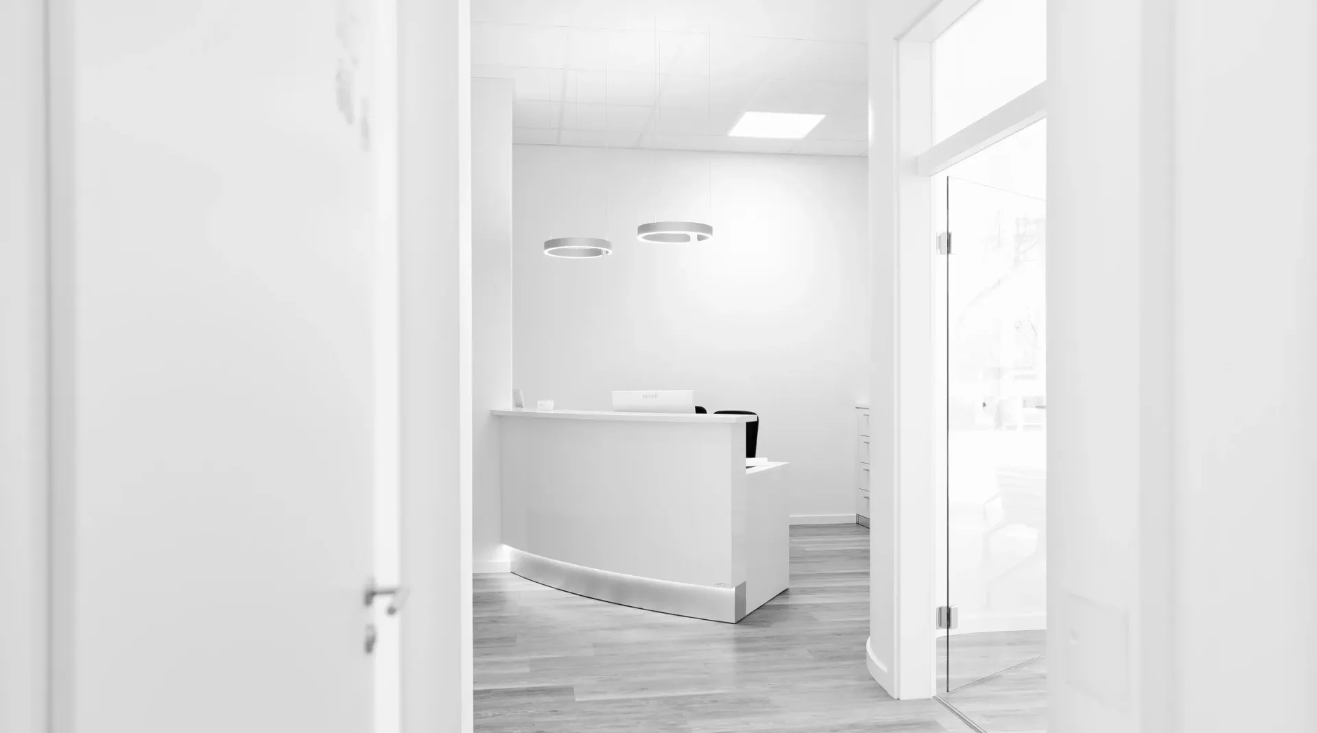 Empfangsbereich der Praxis in schlichter, weißer Gestaltung.