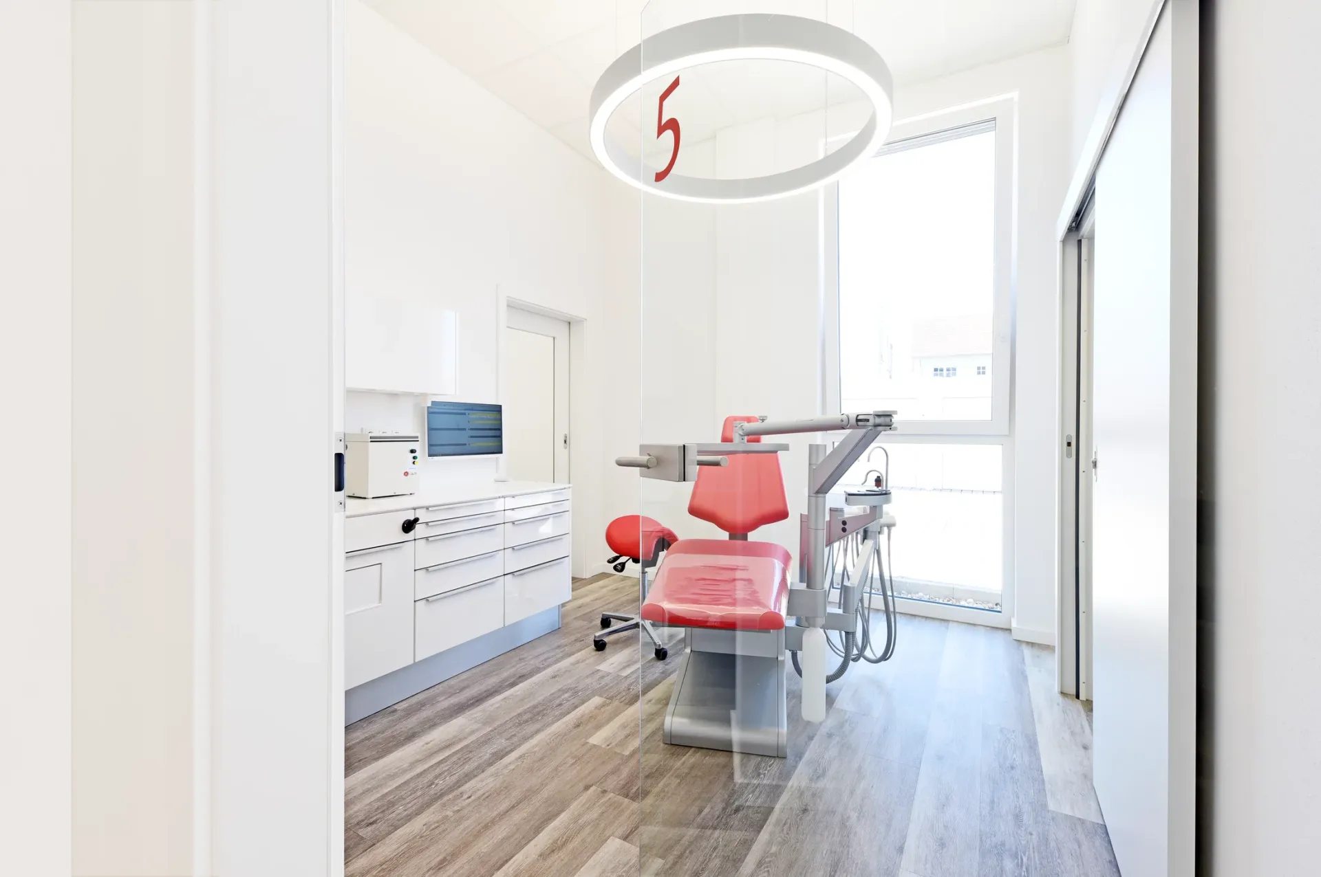 Behandlungszimmer 5 mit roter Behandlungseinheit.