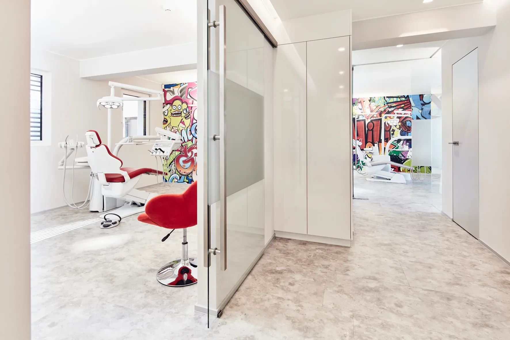 Blick aus dem Flur auf zwei Behandlungsräume mit unterschiedlichen Wandgraffiti.