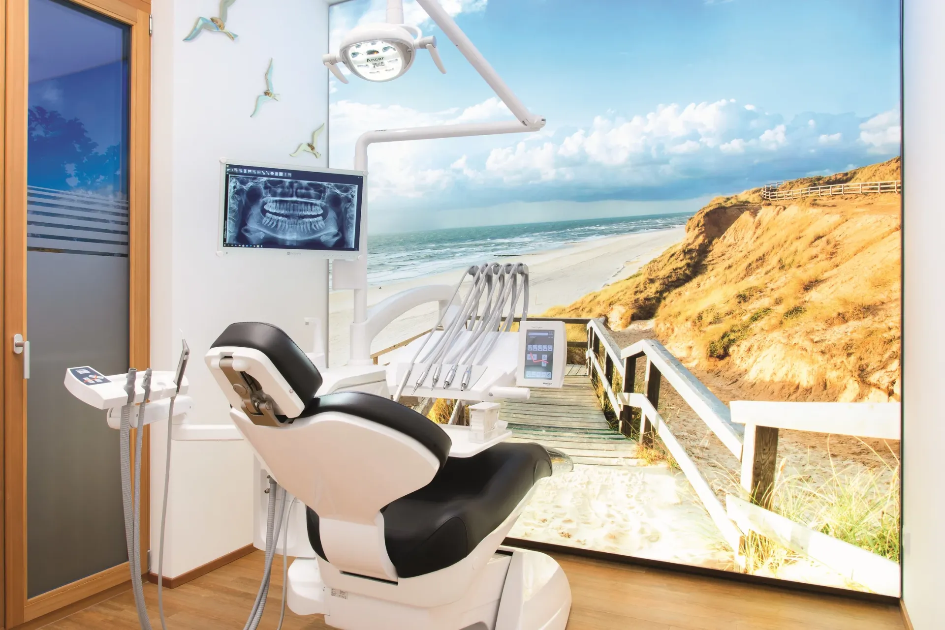 Behandlungszimmer mit Blick auf ein großes Wandbild von Strand und Meer.