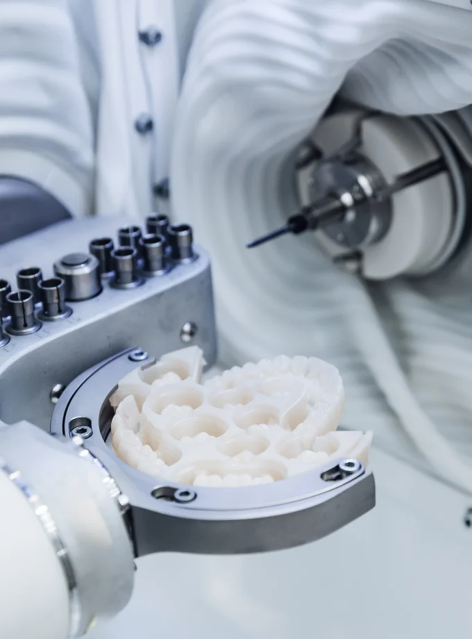 Eine Nahaufnahme einer CAD/CAM Dentalfräse, die in einem Labor ein künstliches Gebiss formt.
