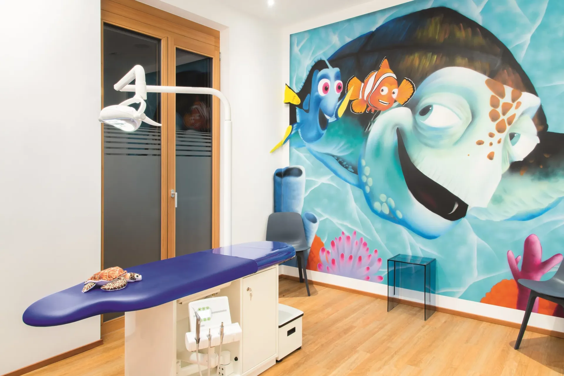 Behandlungszimmer mit Unterwasser-Thema und Wandmalerei im Stil einer Meereswelt.