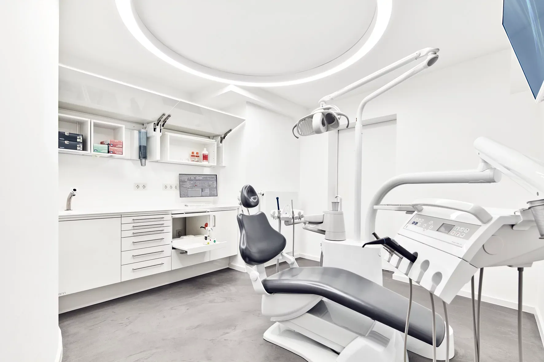 Behandlungsraum mit Wandschränken und Behandlungseinheit.