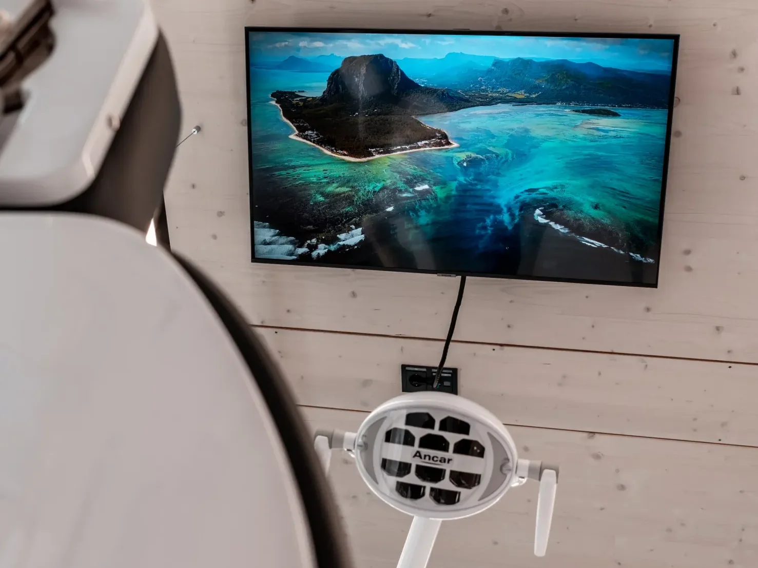 Behandlungsraum mit Behandlungsstuhl und Deckenbildschirm.